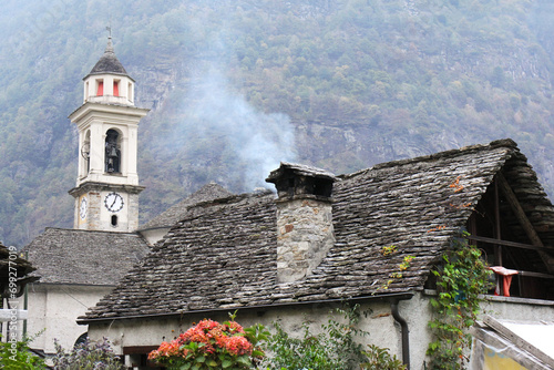 Stone cottage with a church tower in Sonogno, Lavertezzo Vally, Ticino, Switzerland photo