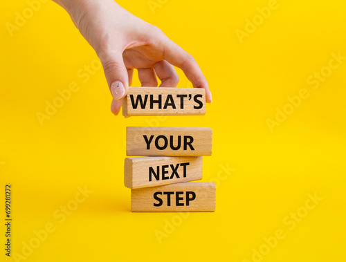 What is your next step symbol. Wooden blocks with words What is your next step. Businessman hand. Beautiful yellow background. Business concept. Copy space. © Natallia