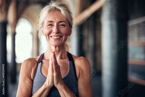 Smiling Mature woman meditating posing at a gym, pilates or yoga studio