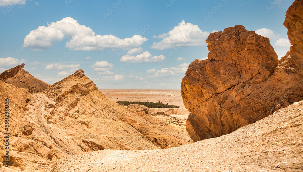 Panoramic view of scenery Sahara desert, sandy rocks and stones, sunny day. Photo of landscape desert hills with sand, blue sky with clouds. Sahara, Tozeur city, Tunisia, Africa. Copy ad text space