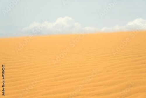 Sand dune in the desert with clouds in the background.