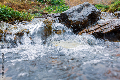 Raging water of a fast mountain river in a picturesque beautiful mountainous area, flowing water with splashes, selective focus