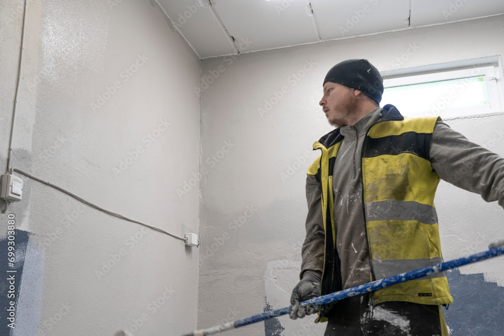 ranquil Gray Elegance: Skilled Artisan in Working Clothes Paints Grand Room Wall with Precision. ranquil Gray Elegance: Skilled Artisan in Working Clothes Paints Grand Room Wall with Precision.