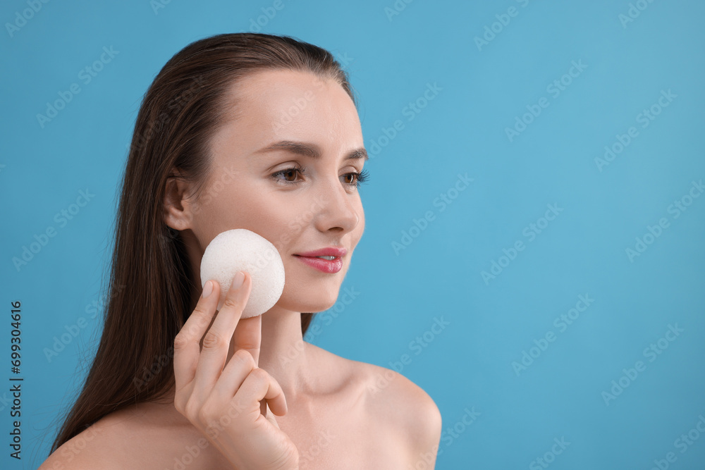Young woman holding face sponge on light blue background. Space for text Young woman holding face sponge on light blue background. Space for text