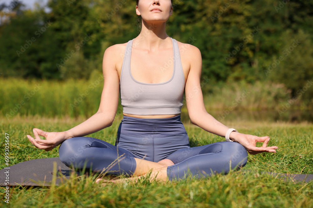 Woman practicing yoga on mat outdoors, closeup. Lotus pose Woman practicing yoga on mat outdoors, closeup. Lotus pose