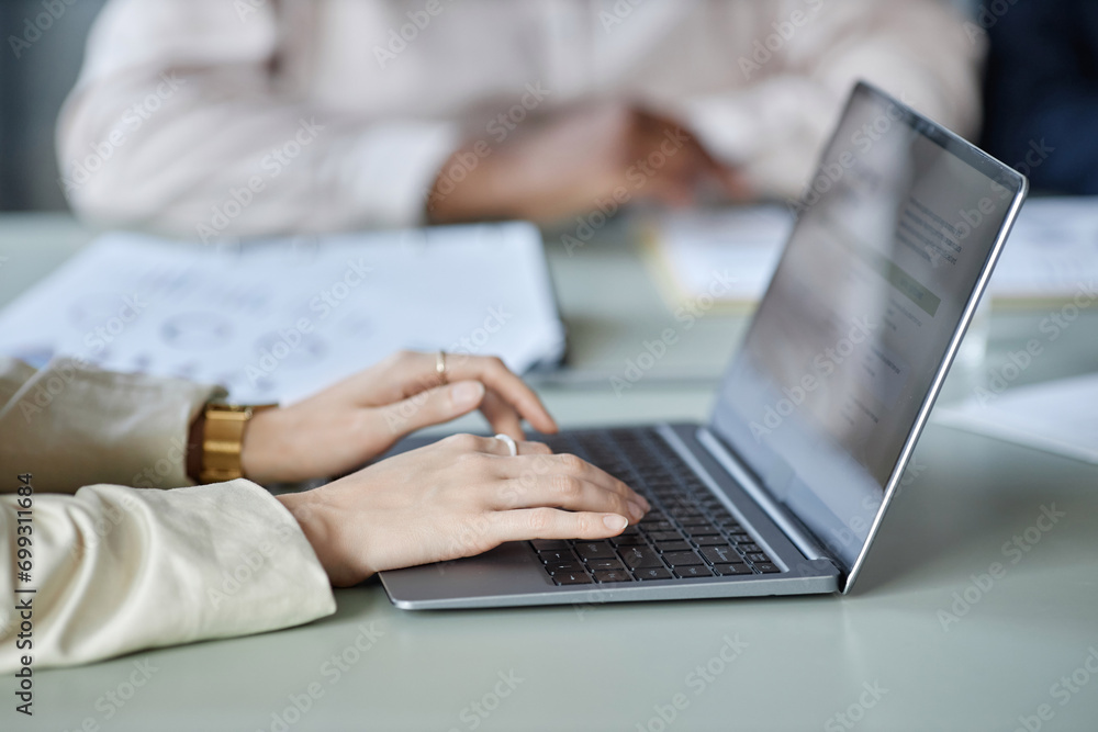 Close up shot with side view of unrecognizable female hands typing on laptop keyboard while sitting at desk in office Close up shot with side view of unrecognizable female hands typing on laptop keyboard while sitting at desk in office