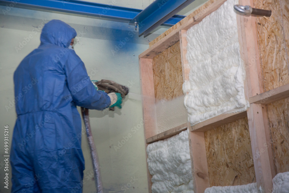 Insulation of walls with foam, energy and heat saving of walls, worker treats walls with foam