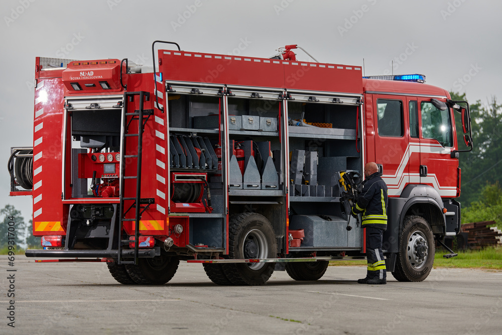 Fototapeta premium A firefighter meticulously prepares a modern firetruck for a mission to evacuate and respond to dangerous situations, showcasing the utmost dedication to safety and readiness in the face of a fire