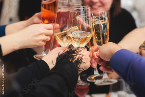 Group of guests celebrate and raise glasses, cheering with alcohol glasses with wine and champagne in the restaurant on corporate christmas birthday party event or wedding celebration photo