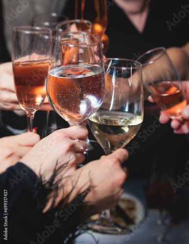 Group of guests celebrate and raise glasses, cheering with alcohol glasses with wine and champagne in the restaurant on corporate christmas birthday party event or wedding celebration