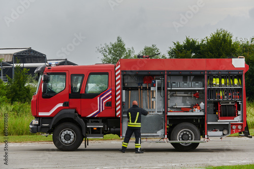 A firefighter meticulously prepares a modern firetruck for a mission to evacuate and respond to dangerous situations, showcasing the utmost dedication to safety and readiness in the face of a fire