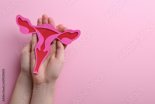 Reproductive medicine. Woman holding paper uterus on pink background, top view with space for text photo