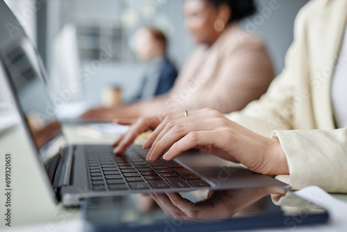 Close up shot of unrecognizable female company worker working on laptop while sitting at office table