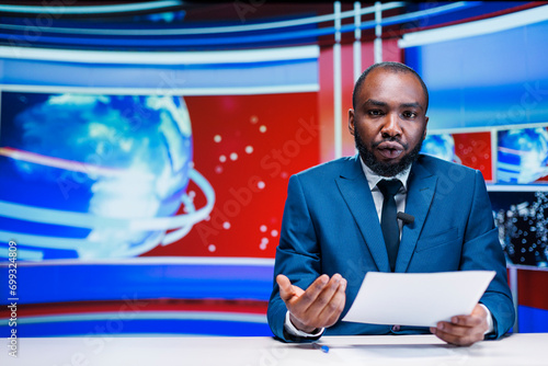 News reporter delivering breaking news on media segment in newsroom, reading important headlines of the day on international tv program. Man journalist presenting daily events live.