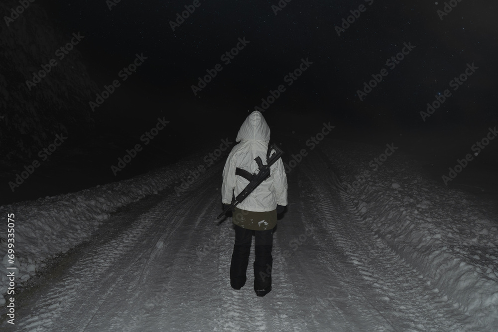 A girl soldier in winter camouflage with an AK 12 assault rifle behind her back. A girl soldier in winter camouflage with an AK 12 assault rifle behind her back.