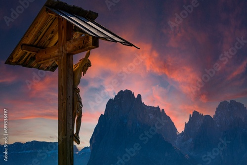 Wooden carved Christs Martyrdom, behind the peaks of the Sassolungo group in the sunset, Alpe di Siusi, Val Gardena, Dolomites, South Tyrol, Italy, Europe photo