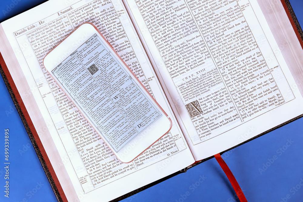 24 DECEMBER 2023 Washington DC USA. An open reading Bible, smartphone are placed on wooden table for study 24 DECEMBER 2023 Washington DC USA. An open reading Bible, smartphone are placed on wooden table for study