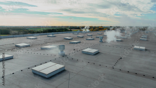  Large roof of factory with roof ventilators, steam coming out from them, drone shot from above