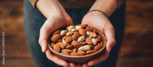 Nut-filled bowl being held by hands, representing healthful eating. photo