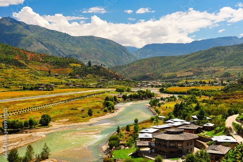 A panoramic view of the airport and the Paro Valley, Bhutan. Landscape with Mountain, river, green meadows and agricultural land, blue sky with white clouds.