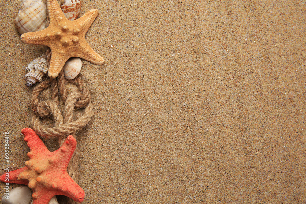 Beautiful sea stars, shells and ropes on sand, flat lay. Space for text Beautiful sea stars, shells and ropes on sand, flat lay. Space for text
