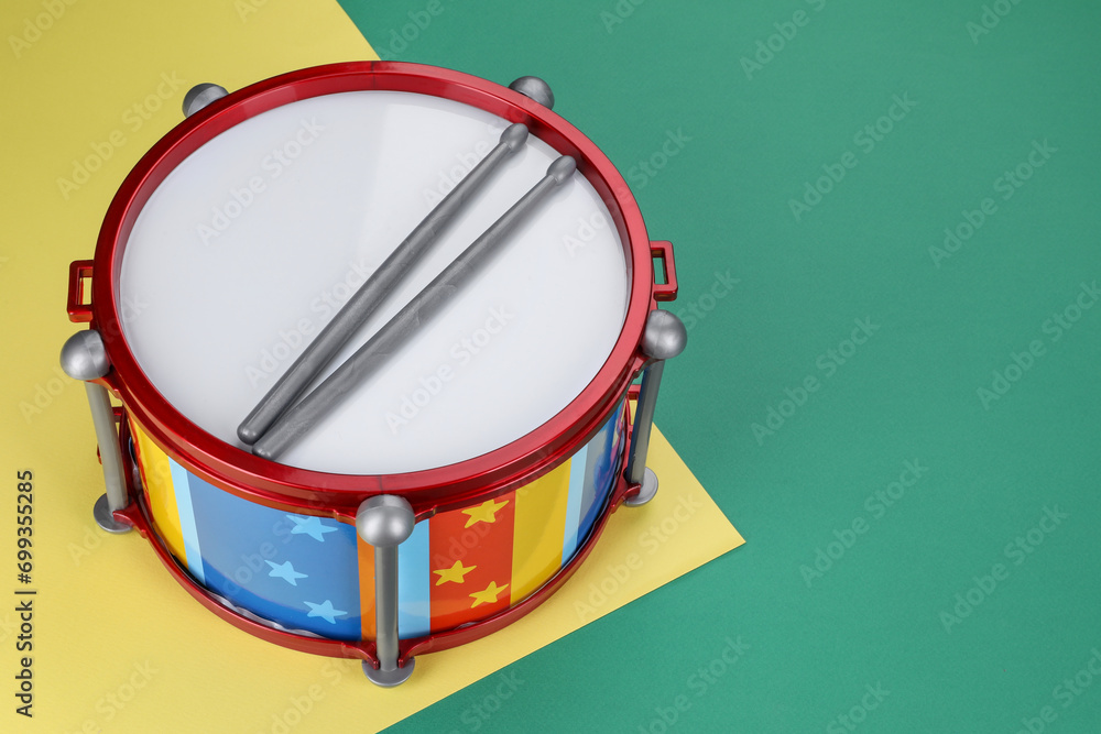 Children's drum with drumsticks on color background. Space for text Children's drum with drumsticks on color background. Space for text