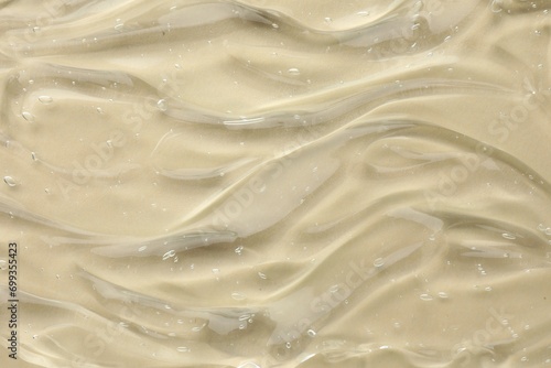 Clear cosmetic gel on beige background, top view