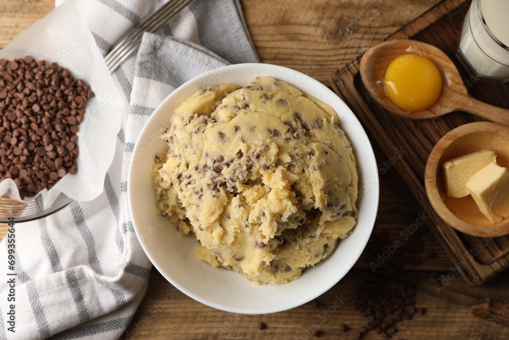 Chocolate chip cookie dough in bowl and ingredients on wooden table, flat lay Chocolate chip cookie dough in bowl and ingredients on wooden table, flat lay