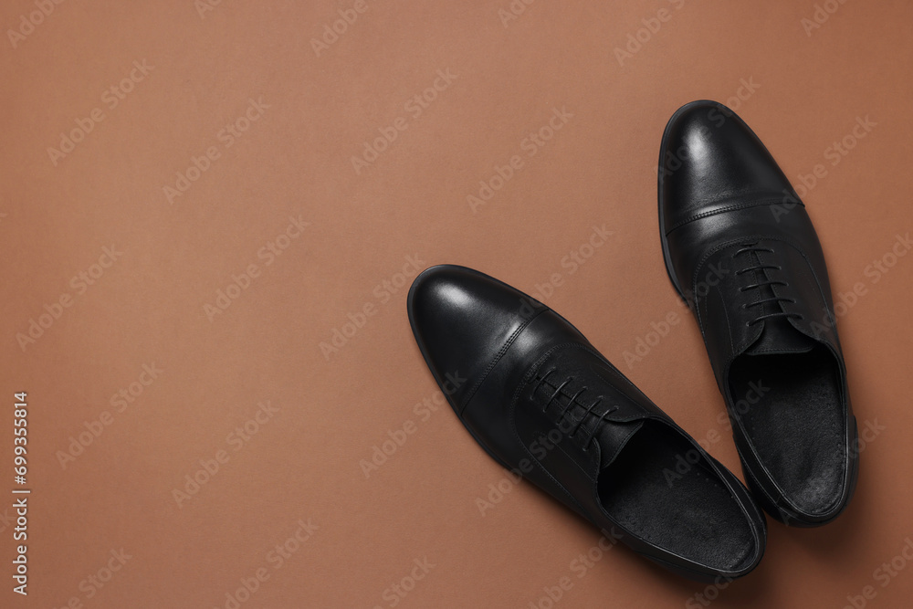 Pair of leather men shoes on brown background, top view. Space for text