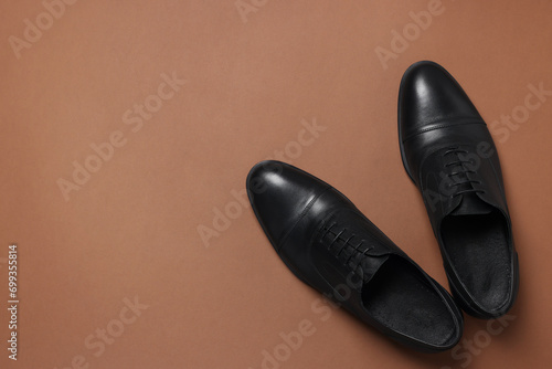 Pair of leather men shoes on brown background  top view. Space for text