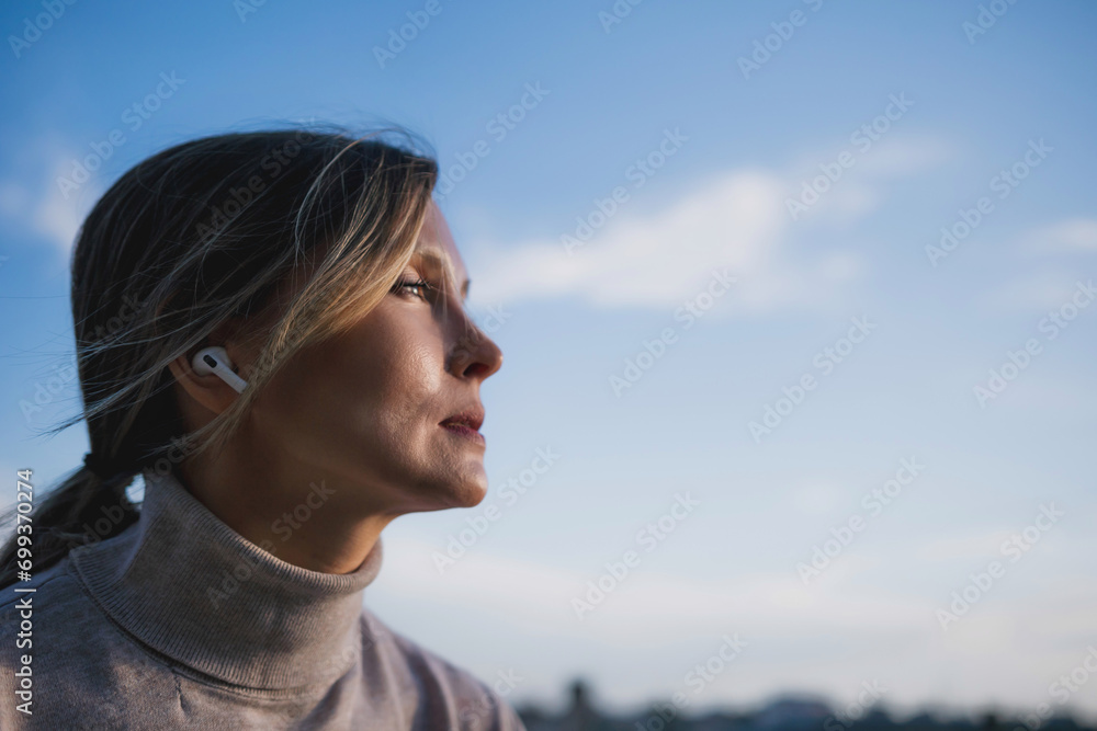 Woman freelancer uses laptop on cement wall outdoors against the sky. The woman to be focused on her work or enjoying some leisure time while using her laptop. Woman freelancer uses laptop on cement wall outdoors against the sky. The woman to be focused on her work or enjoying some leisure time while using her laptop.