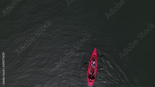 Top view drone shot of a family, parents with two kids, passing by in the frame, practicing kayaking. Gulf of Nicoya, Costa Rica. photo