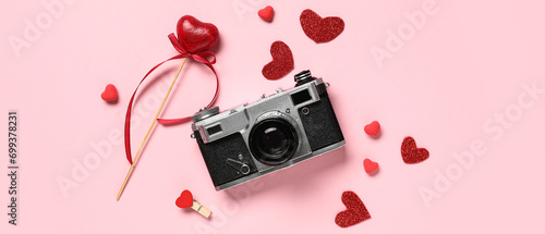 Retro photo camera with hearts on pink background