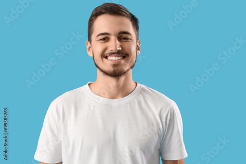 Handsome young man with healthy teeth on blue background. Dental care concept