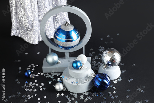 Decorative stands with different Christmas balls and confetti on black background