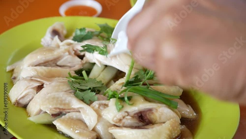 close up view while use spoon and fork to grab homemade singapore hainan chicken in big plate at hawker center,famous dish of singapore delicious Steamed Chicken to eat with rice