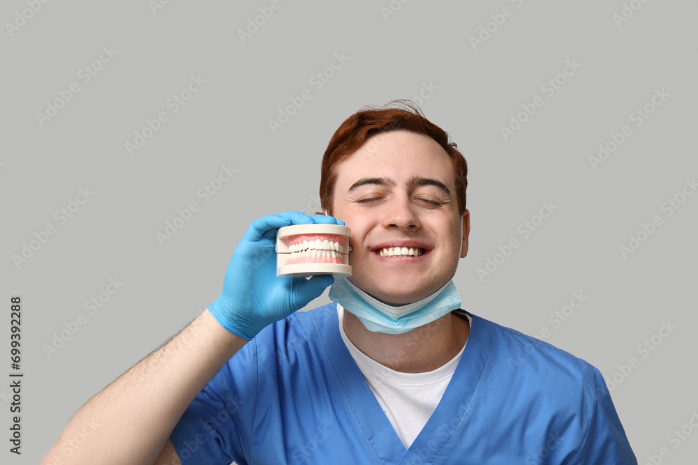 Male dentist with jaw model on grey background. World Dentist Day Male dentist with jaw model on grey background. World Dentist Day