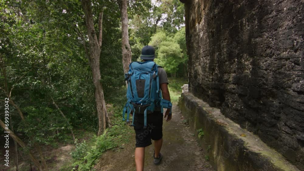 Hiker walking alongside ancient ruins in Guatemala to view Hiker walking alongside ancient ruins in Guatemala to view