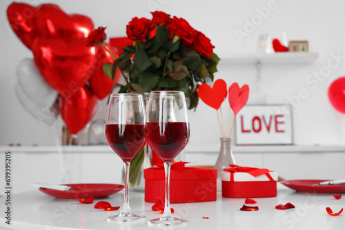 Festive table serving with glasses of wine, roses, petals and gift boxes. Valentine's Day celebration