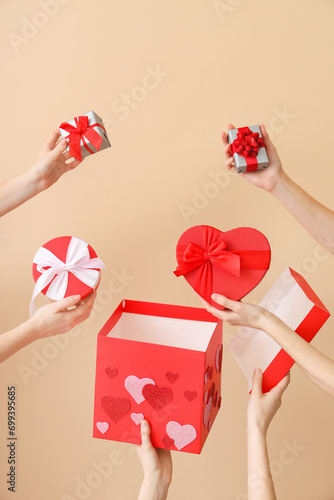 Female hands with gift boxes on beige background. Valentine's Day celebration