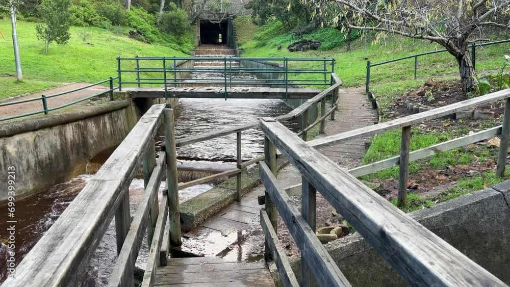 Stormwater river flowing under the roadway through the park with various footbridge crossings and footpaths Stormwater river flowing under the roadway through the park with various footbridge crossings and footpaths