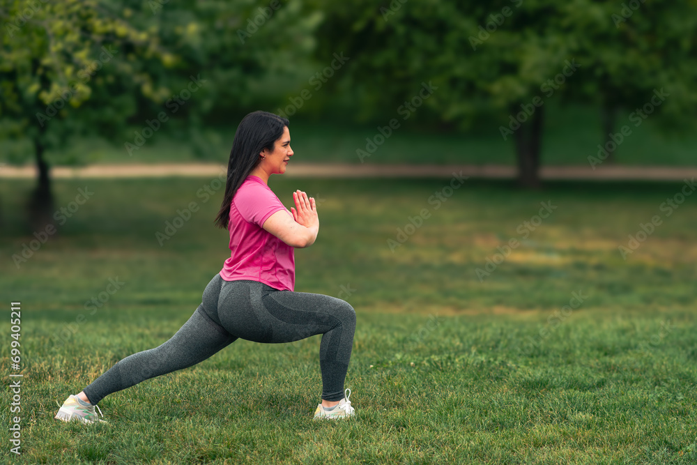 beautiful brunette woman doing stretching, yoga and exercises, in a green grass park wearing sportswear beautiful brunette woman doing stretching, yoga and exercises, in a green grass park wearing sportswear