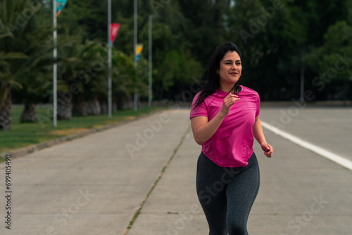 beautiful brunette latin woman running through a park, doing exercises, wearing sportswear