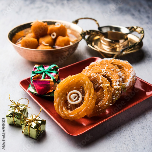 indian sweet jalebi imarti laddu and gujiya served together over white background photo