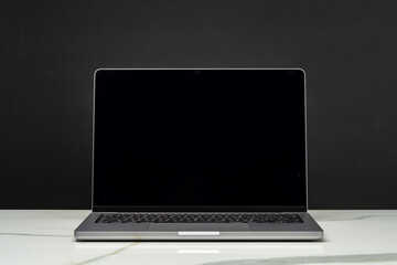Open laptop with black screen against black background