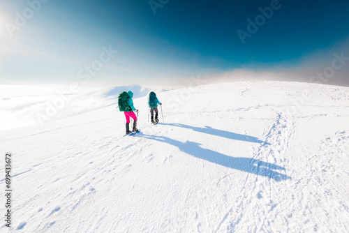 climbers climb the mountain. Winter mountaineering. two girls in snowshoes walk through the snow.