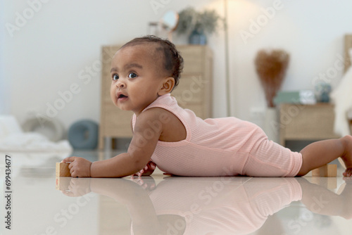 Portrait of smiling African cute toddle baby infant kid crawling on floor in bedroom at home. Happy child with reflection on the floor, kid at home, happy childhood photo