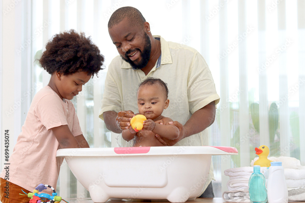 Happy African family, father bathing kid in tub, dad and son brother washing and cleaning little toddler girl daughter child in bath. Toddle baby infant has fun while taking bubble bath in bathroom. Happy African family, father bathing kid in tub, dad and son brother washing and cleaning little toddler girl daughter child in bath. Toddle baby infant has fun while taking bubble bath in bathroom.