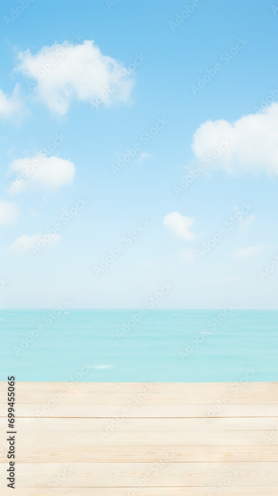 Wooden deck leading to a tranquil turquoise sea under a blue sky with fluffy clouds