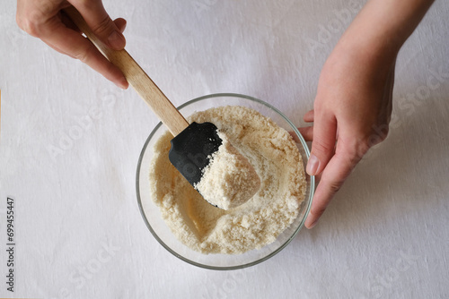 female cook stirring almond flour in a glass plate top view